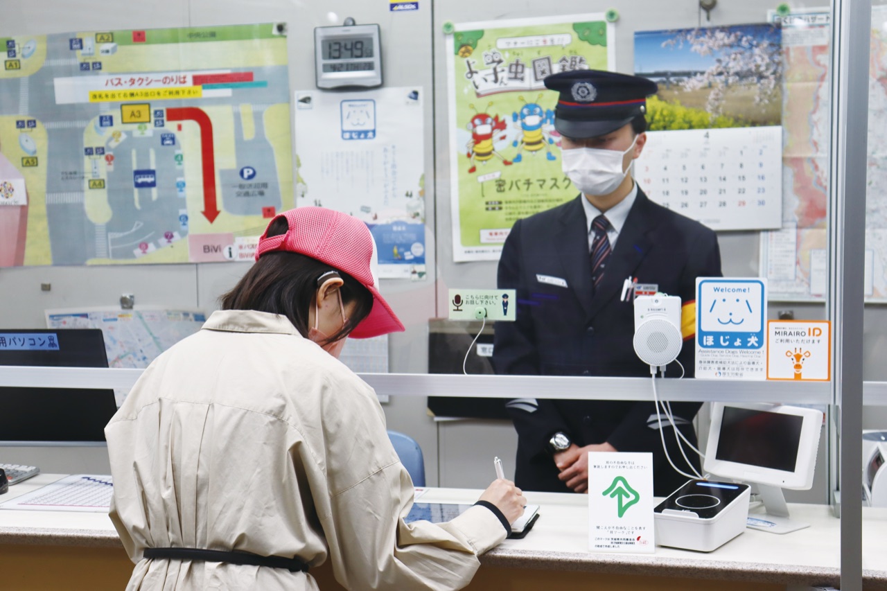 駅の窓口で筆談や支援機器を用いてやりとりする様子